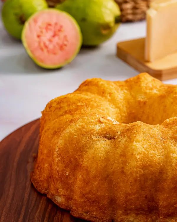 Bolo de queijo dourado, com goiaba e queijo ao fundo