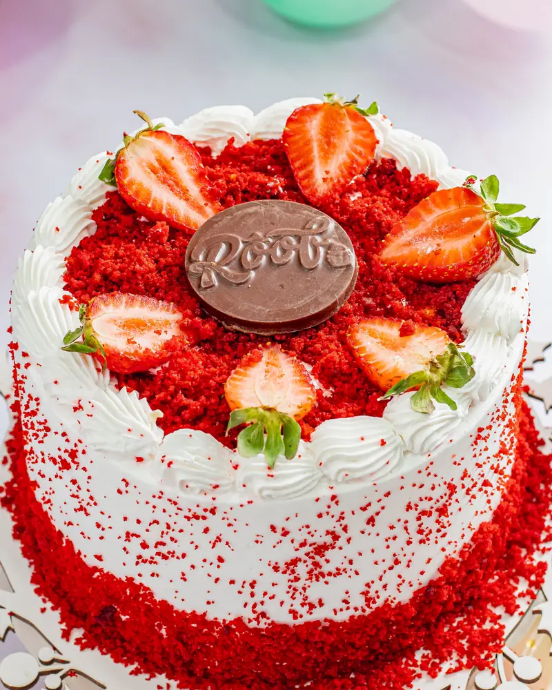Torta Red Velvet decorada com chantilly, morangos e farofa vermelha na lateral
